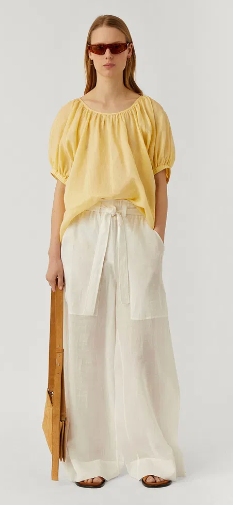 Woman wearing a yellow blouse and white pants with text about 'Modern Love' and 'Joseph' clothing.